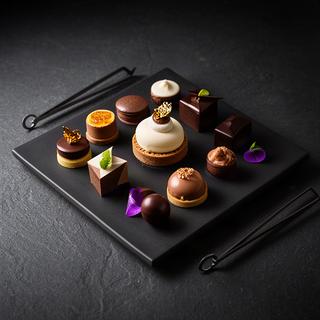 Petit fours de autor y mignardises colocados sobre una vajilla oscura de restaurante